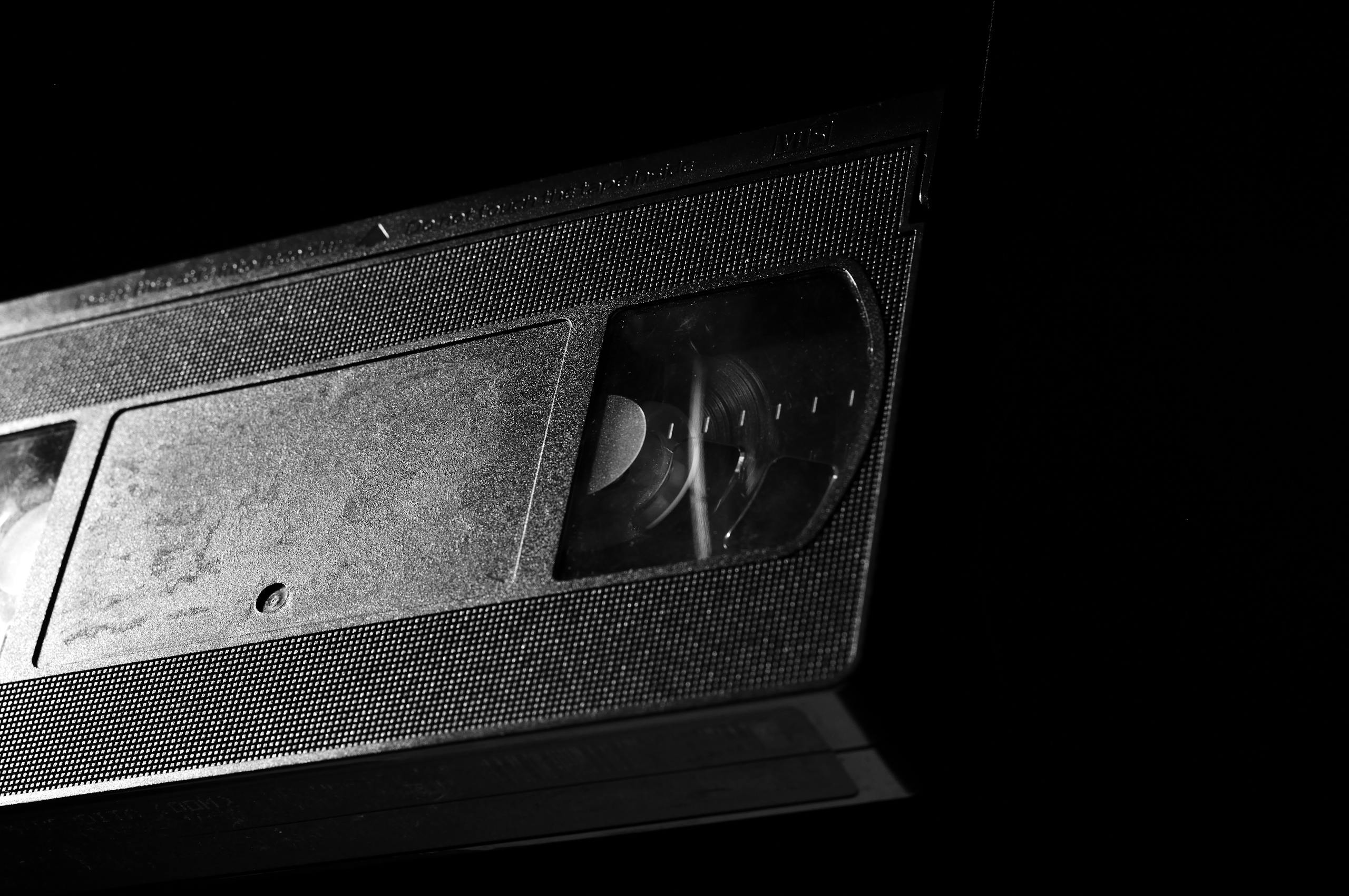 High-contrast close-up of a retro VHS tape against a dark background.